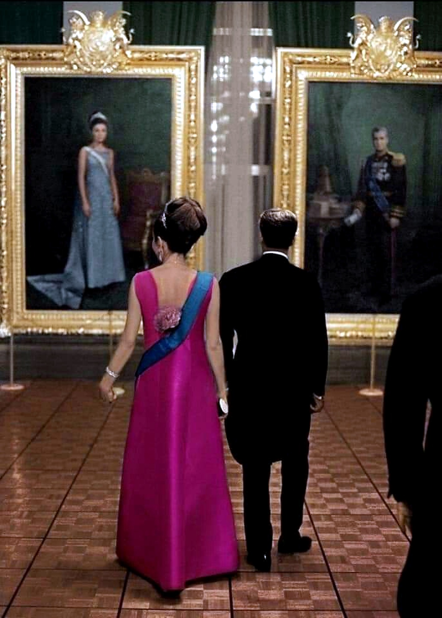 Farah Pahlavi walking past her own portrait.