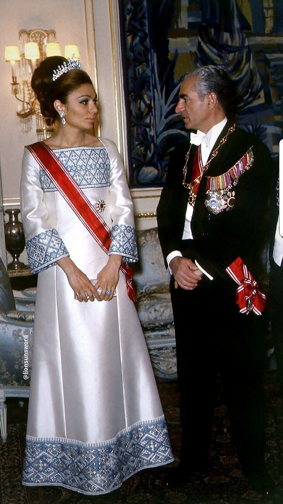 Farah Pahlavi in white and blue embroidery with the Shah.