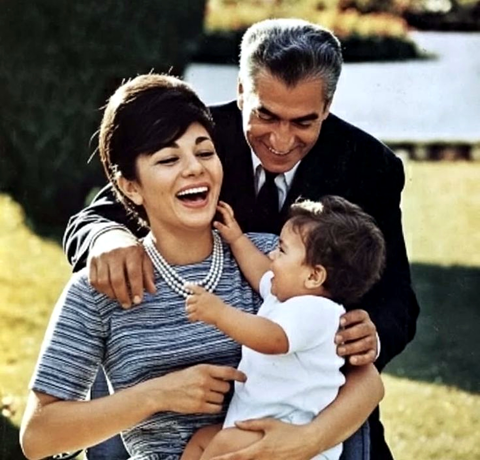 Farah, Mohammad Reza Shah, and an infant in the garden.